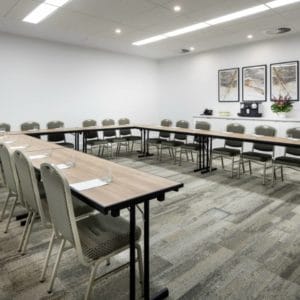 Conference room tables and chairs set up in a U shape ready for a presentation or meeting