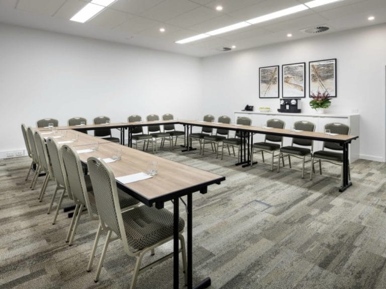 Conference room tables and chairs set up in a U shape ready for a presentation or meeting