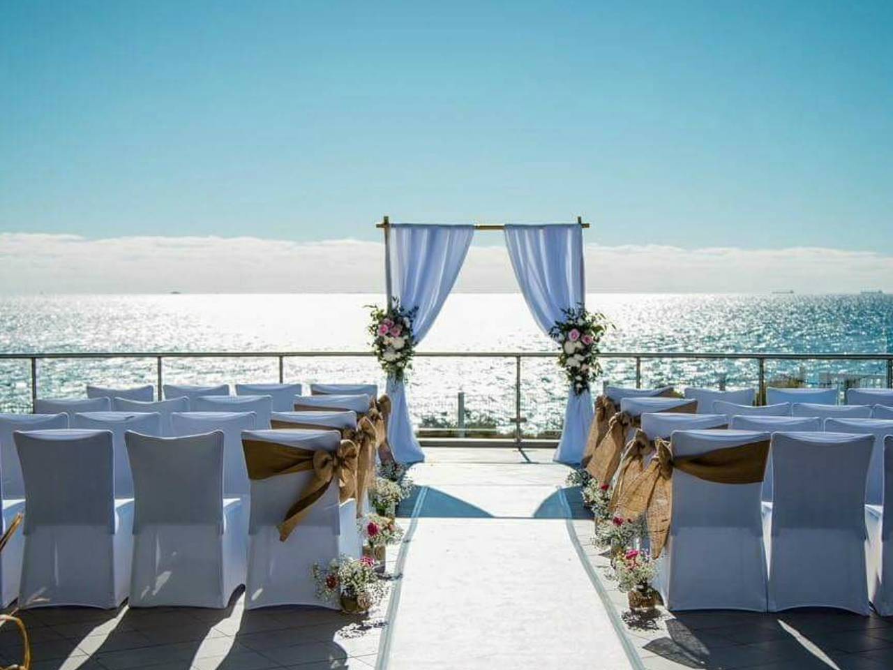 A Alter Leading Up to the Sea With White Chairs For The Guests.