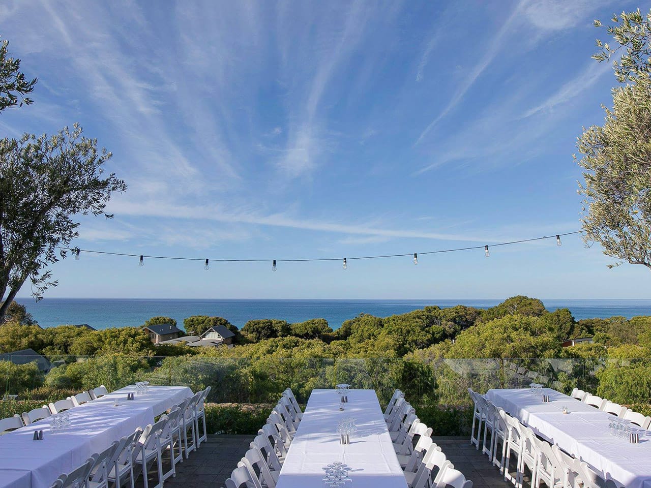 A Wedding Dinner Tables Set Up With The Ocean In The Background.