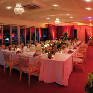 Tables And Chairs In A U-shape Style With Centerpieces, Candle Lit And Red Lightning Inside The Entire Function Room