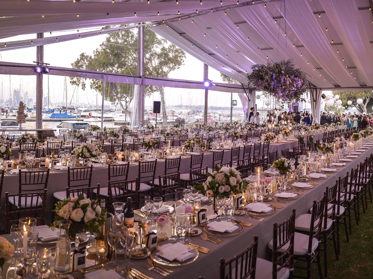 Long Tables with Chairs, Centerpieces, String Lights, Hanging Flower And Ceiling Drapping