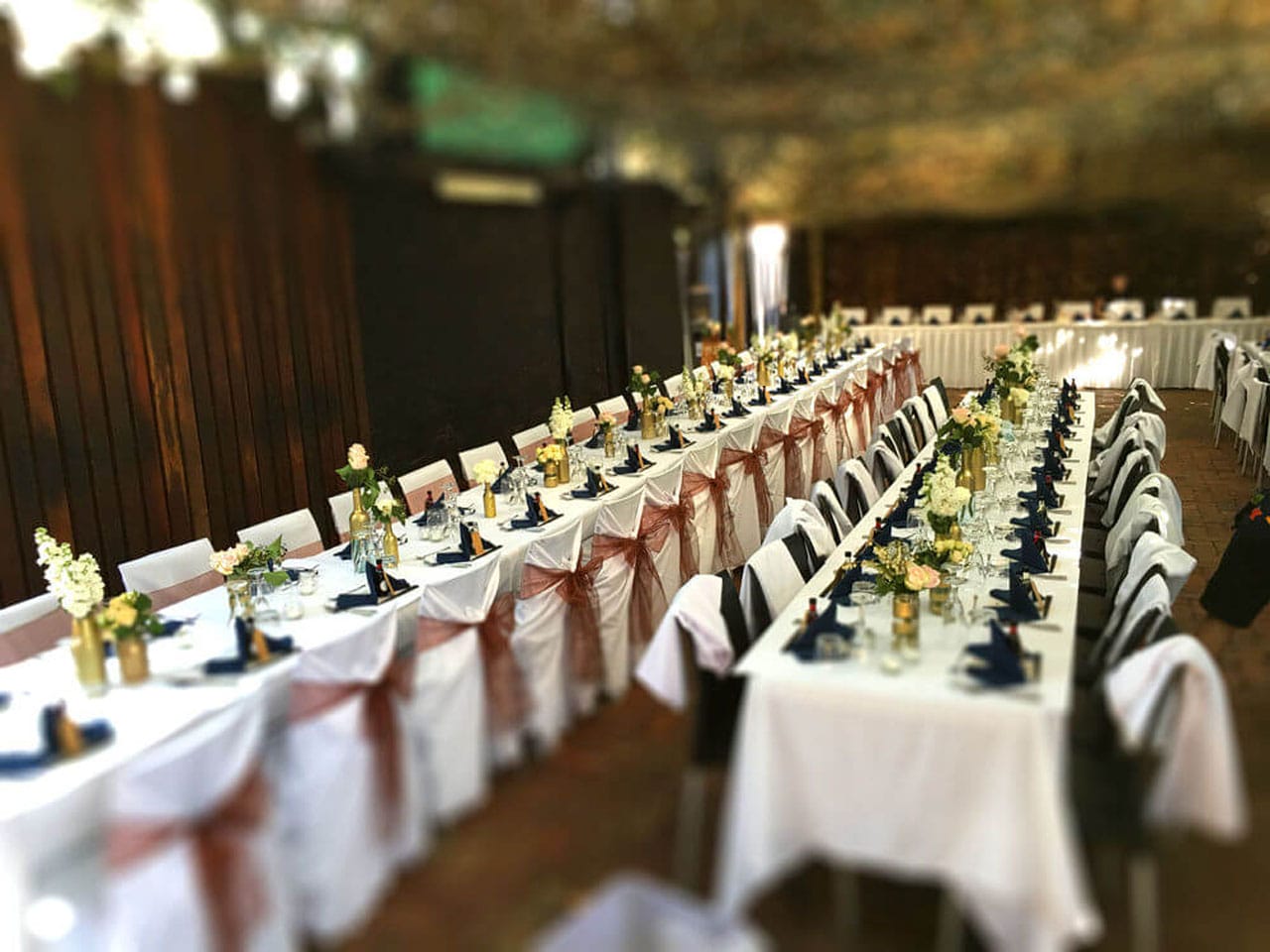 Long Tables Fully Set With Cutlery and Green Napkins In The Open Air Function Space