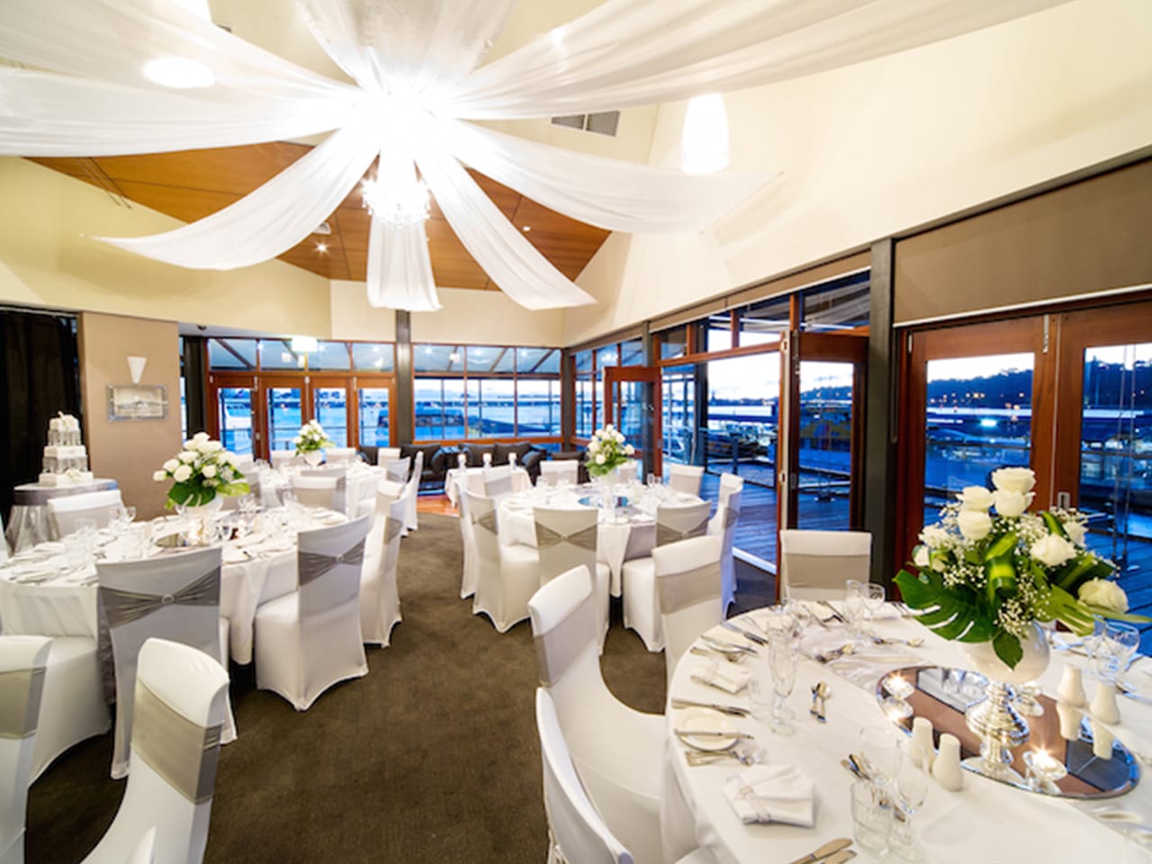 Chairs And Tables In Banquet Style Inside The Function Venue With Glass Windows And Ceiling Draping