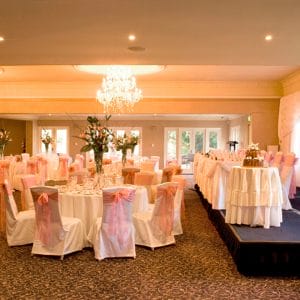 Long Table, Cake Table On Stage And Banquet Style Setup Inside The Function Room With Chandeliers