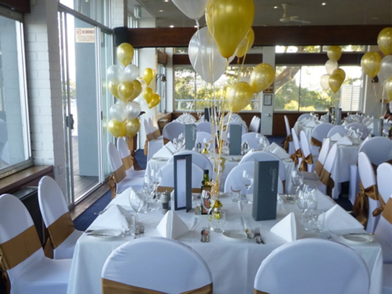 White And Yellow Theme In Tables And Chairs With Balloons Inside The Function Room