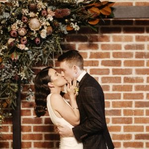 Bride and groom kissing under bouquet