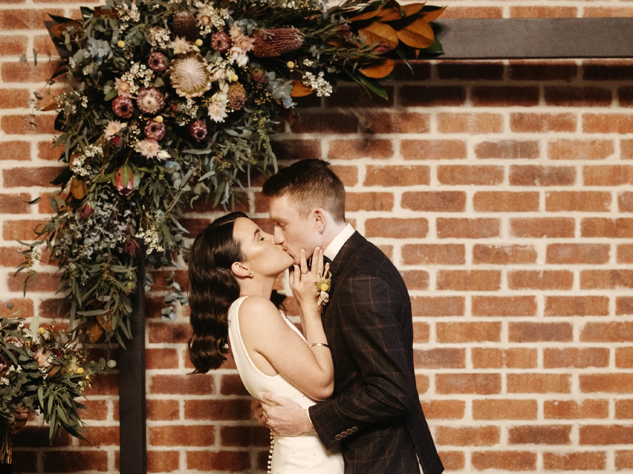 Bride and groom kissing under bouquet