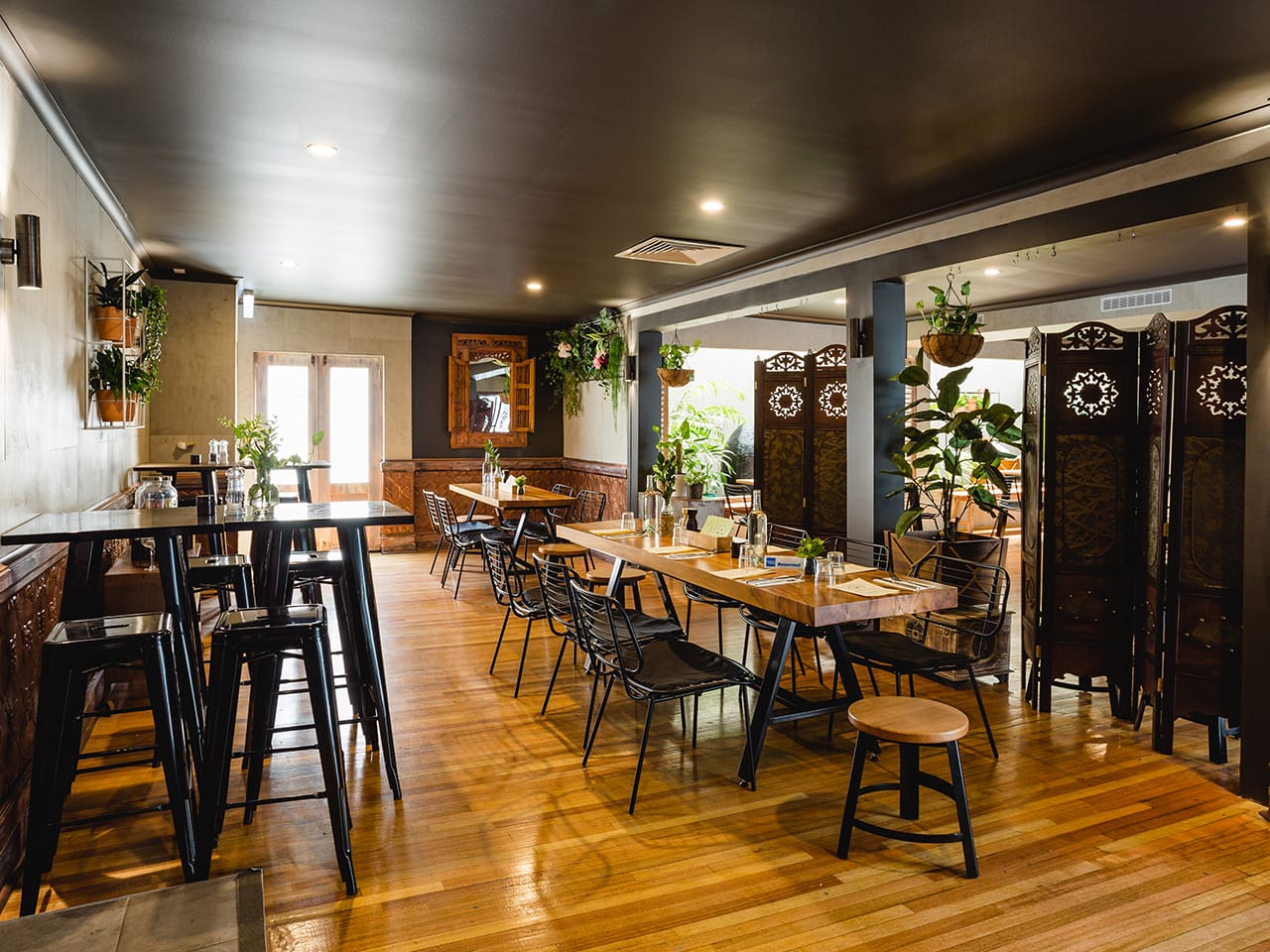 High Tables And Chairs With Regular Tables And Chairs On The Other Side And Indoor Hanging Plants Inside The Function Room