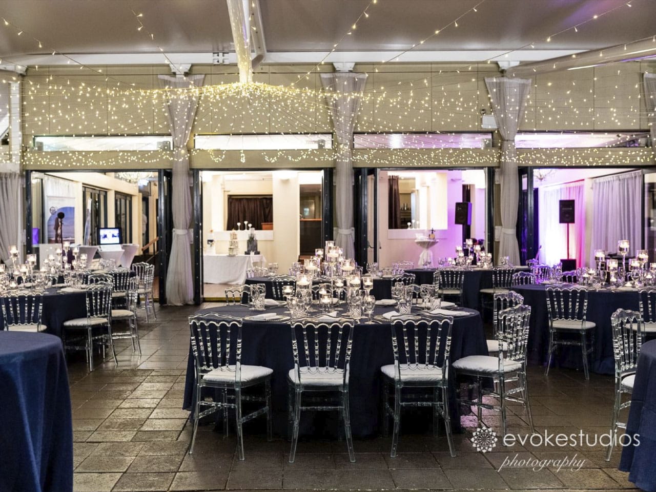 Chairs And Tables In Banquet Style With String Lights Inside The Function Room