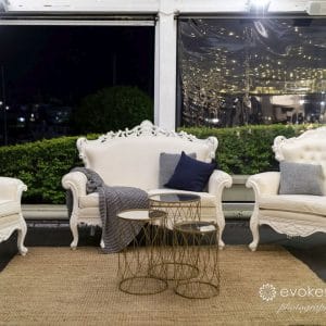 White lounge chairs at window at night time inside function room