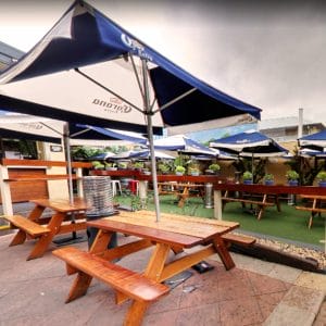 Wooden Tables And Chairs With Umbrellas And Green Plants In The Outdoor Function Venue