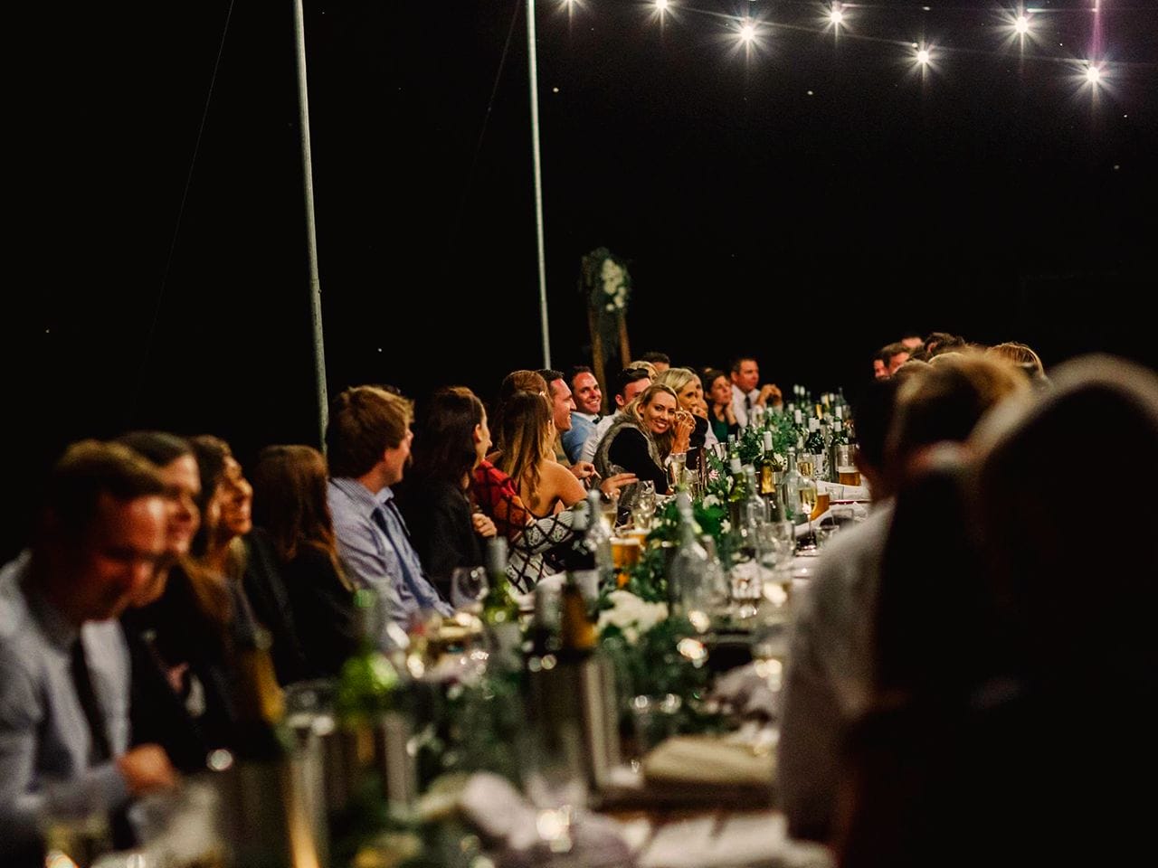 Guests Enjoying The Evening Seated In A Long Table