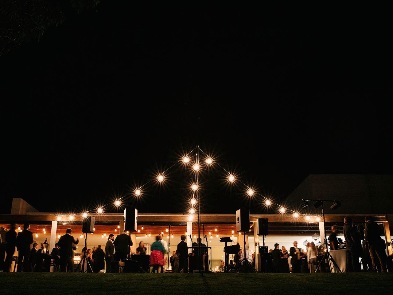 Guests Enjoying The Evening Outside The Function Room With String Lights