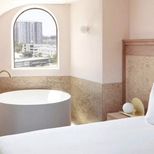 Hotel bedroom with round bath and arched window overlooking Brisbane