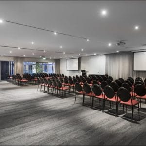 Conference room with rows of black and red seats and projector screen