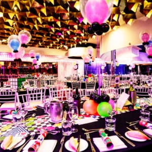 Black tables set for an event with balloons decorating each table
