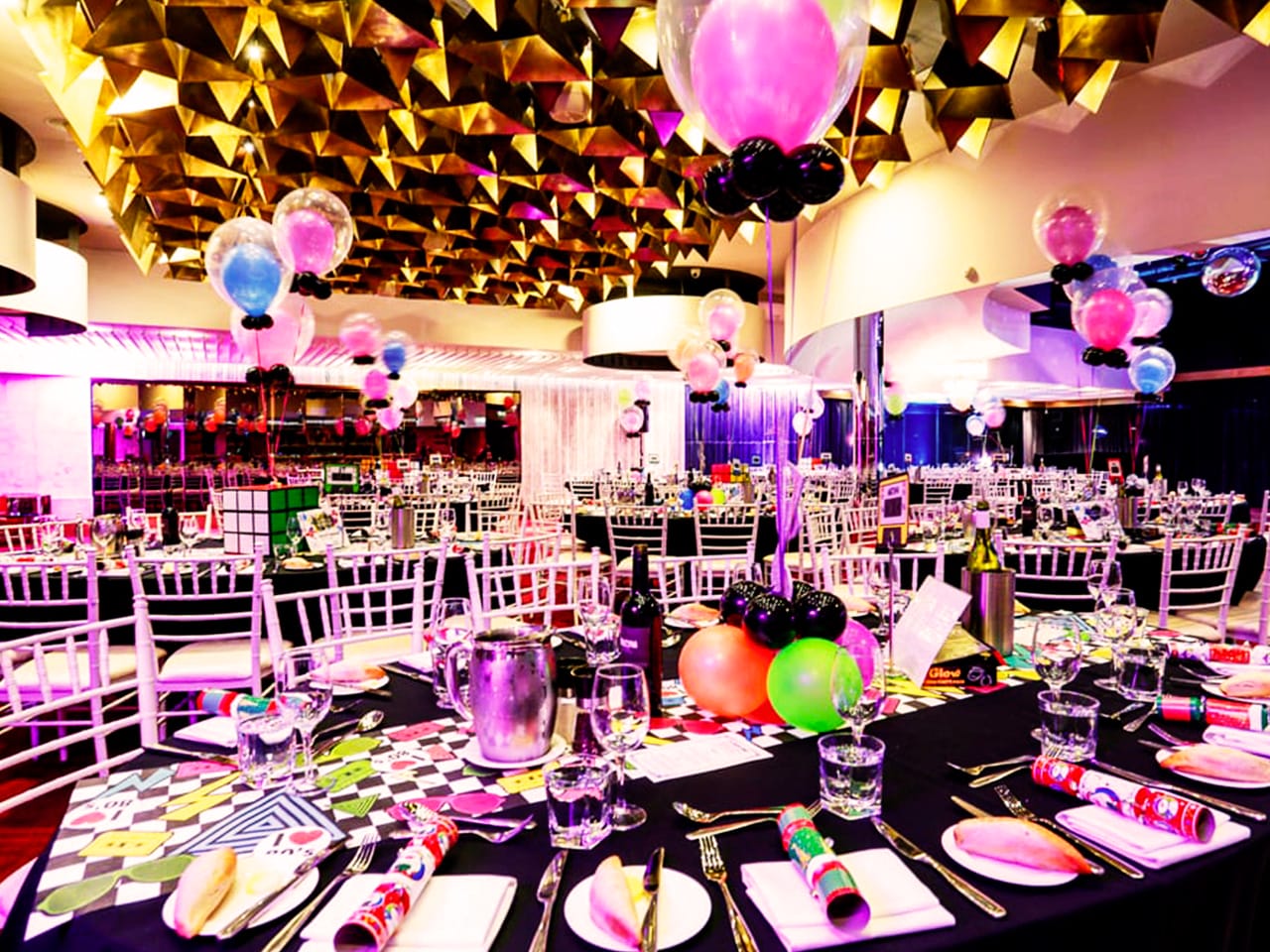 Black tables set for an event with balloons decorating each table