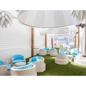 Semi-outdoor function room with white decor and blue and white individual seating with round tables