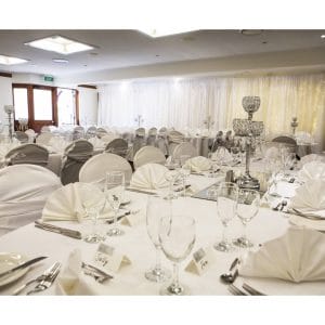 Room set for wedding reception with white tables and chairs