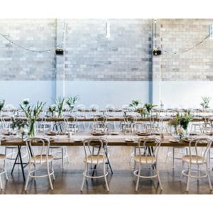 Wedding venue with long tables decorated for wedding with overhead light bulbs