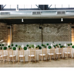 Long tables with black chairs decorated for wedding function