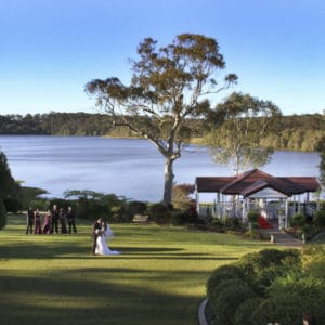 Lakeside wedding ceremony with bride and groom on lawn