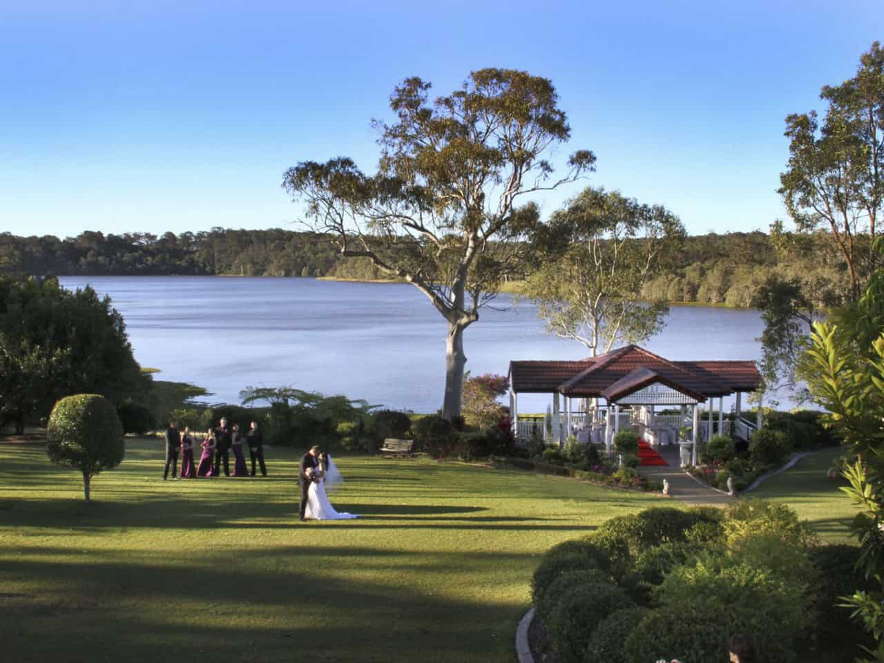 Lakeside wedding ceremony with bride and groom on lawn